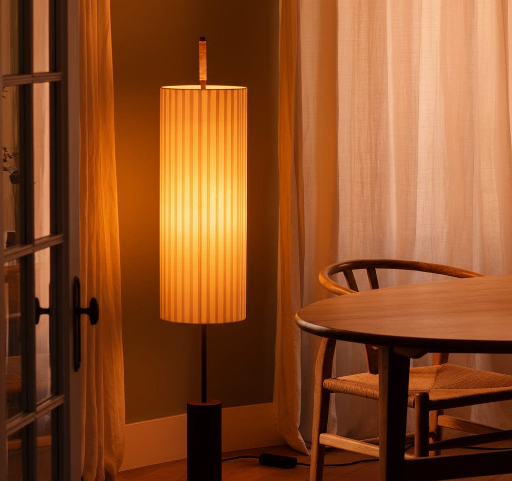 Amber Floor lamp with a warm light in a room with curtains and a wooden table.